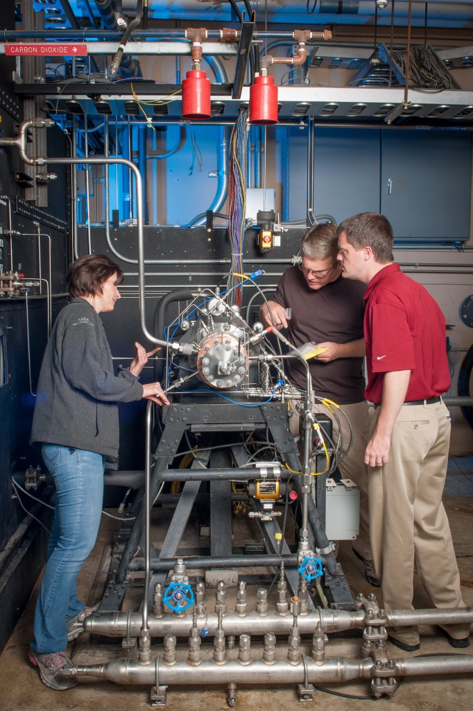 Task lead Tyler Hickman, in red shirt, and technicians inspect the rocket injector assembly as it’s installed in the Rocket Combustion Laboratory at NASA’s Glenn Research Center, Cleveland