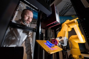 Brad Boyce watches as the Alinstante robotic work cell scans a 3D-printed part to compare what was made to the original design. This test part was devised to push the limits of 3D printing technology. The goal of Alinstante is to speed up the testing of 3D-printed parts and materials science research. (Photo by Randy Montoya)